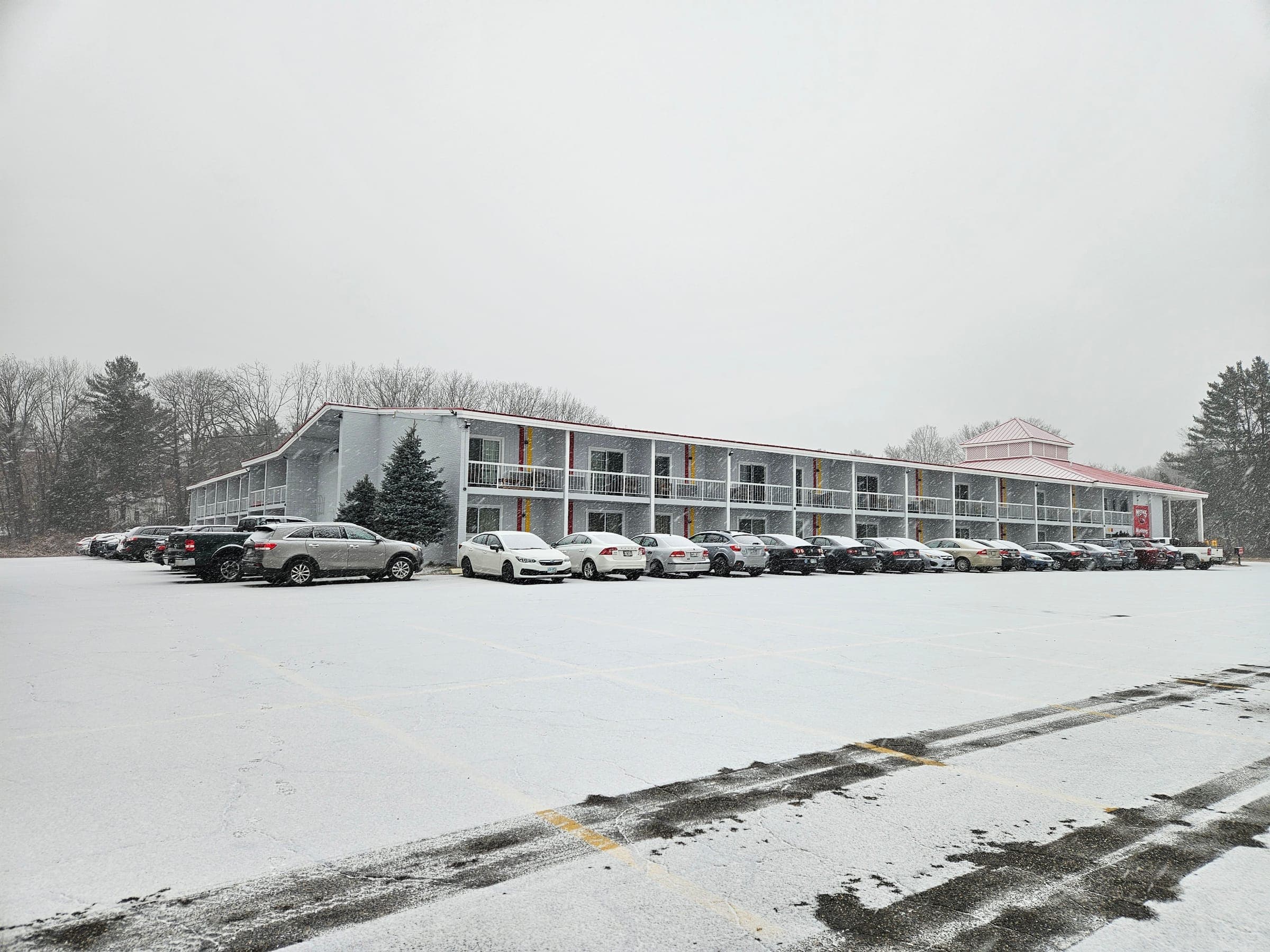Saffron Inn wide-angle exterior view in winter, full property with bare trees and overcast sky, Auburn Maine