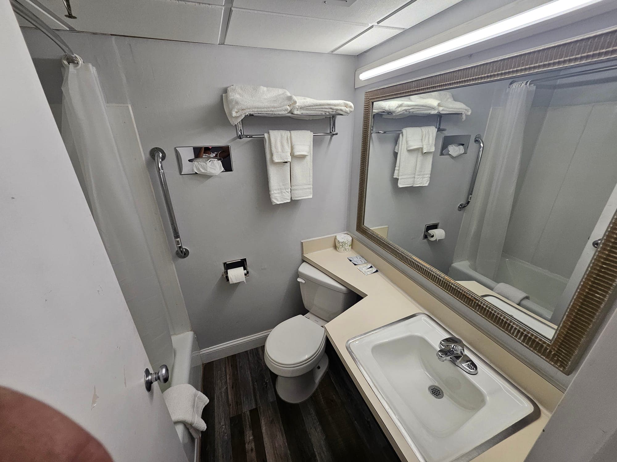 Saffron Inn guest bathroom — full bath with shower/tub combination, grab bars, fresh white towels, framed mirror, gray walls