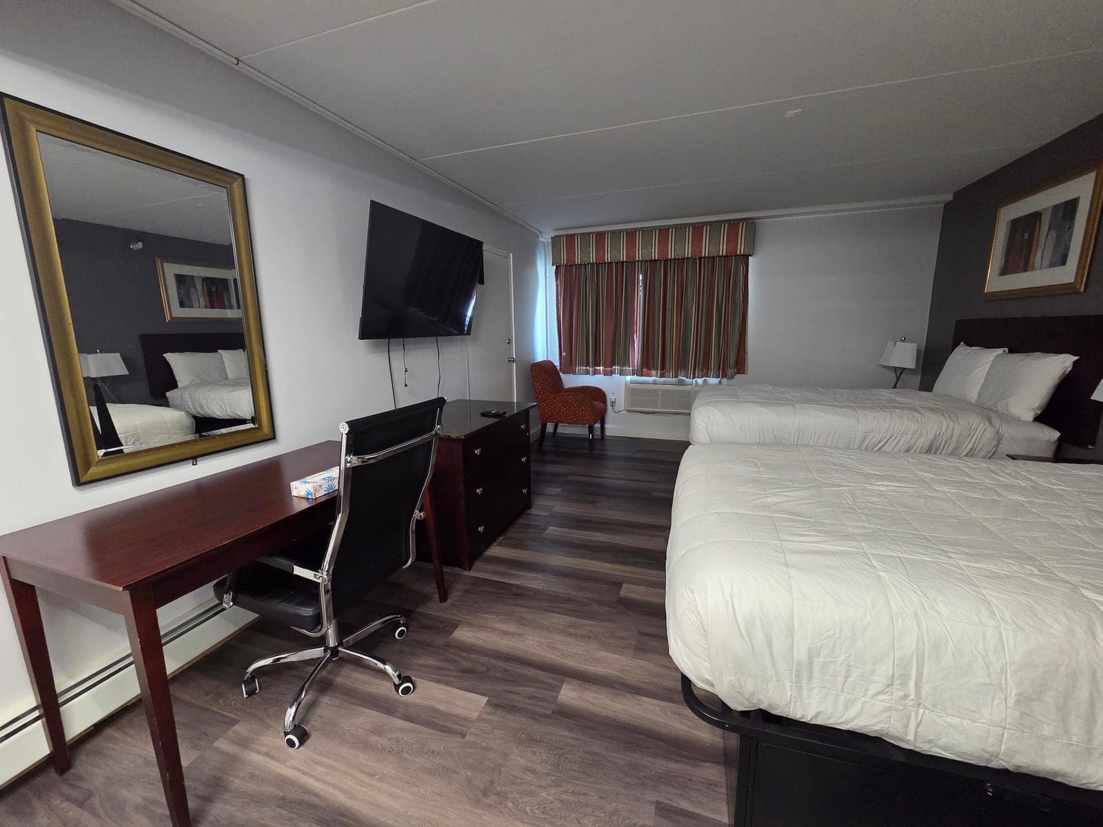 Saffron Inn two-double ground-floor room — view showing the second bed, red armchair, work desk, and large mirror