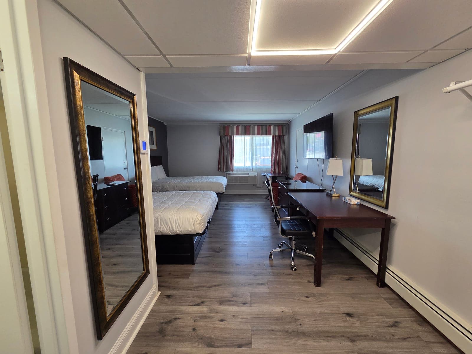 Saffron Inn two-queen ground-floor room — alternate angle with the second bed, red side chair, and window light